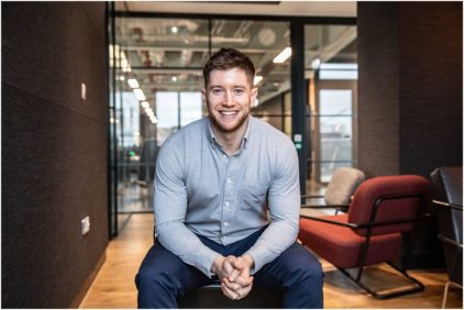 A person sitting on a bench smiling in a modern office setting.