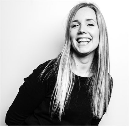 A woman with long hair is smiling in a black and white portrait.