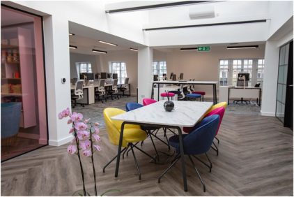 A modern office space with colorful chairs and workstations.