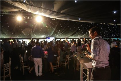 Indoor event with a speaker addressing a crowd under starry lights.