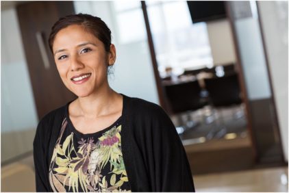Portrait of a woman smiling indoors in an office setting.