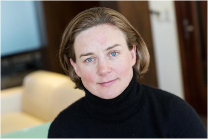 Portrait of a person with short hair wearing a black turtleneck indoors.