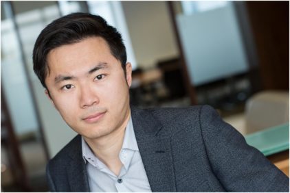 A professional indoor headshot of a person wearing a suit.