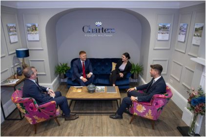 Four people in a modern office lounge are having a discussion.