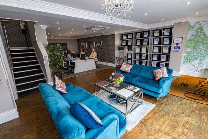 Indoor image of a modern office reception area with blue sofas and a customer service desk.
