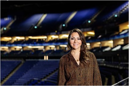Portrait of a person smiling in a large indoor venue with empty seats.