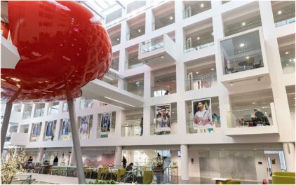 Indoors image of a modern building interior with balconies and a large red structure.