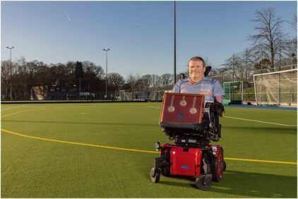 Outdoor portrait of a person in a wheelchair on a sports field.