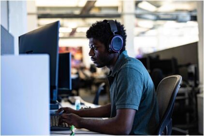 A person wearing headphones working on a computer in an office setting.