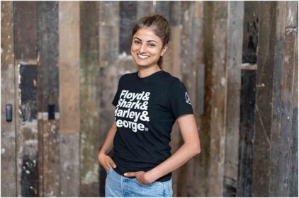 Portrait of a person smiling indoors against a wooden background.