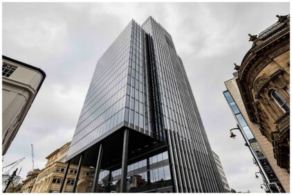 An outdoors image of a modern glass skyscraper against a cloudy sky.