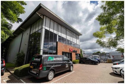 Outdoor image of a modern brick and glass building with parked vehicles.