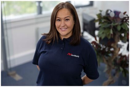 Portrait of a woman smiling indoors, wearing a navy AmWorld shirt.