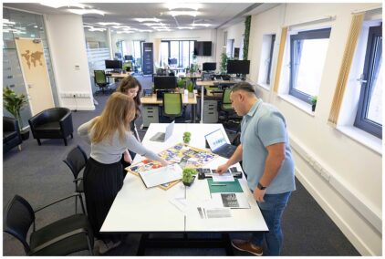 Three people collaborating at a table in an open-plan office.