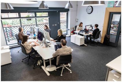 An indoor office scene with six people working at desks.