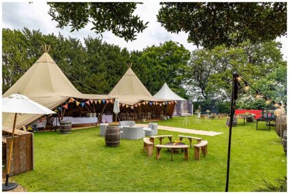 Outdoors image of a festive tent setup on a grassy area surrounded by trees.