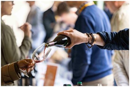 Indoors image of a person pouring red wine into a glass.