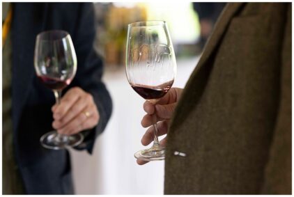 Two people indoors holding glasses of red wine.