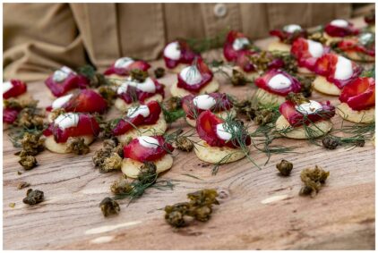 A close-up photo of various appetizers with toppings and garnishes on a wooden board.
