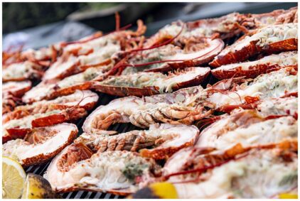 Close-up image of grilled lobsters with lemon slices outdoors.