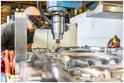 An indoor image of a technician working with a large metal milling machine.