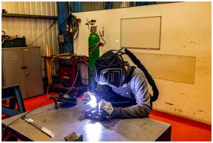A person welding at a workbench indoors.