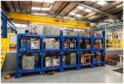 Industrial image of a factory interior with blue racks holding metal molds.