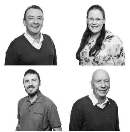 Black and white portrait of four smiling people, two men and two women.
