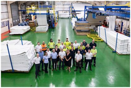 A group of people standing together in an industrial facility, indoors.