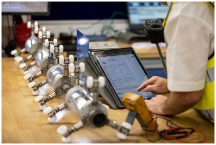 Indoors image of a person working with a tablet and industrial equipment on a table.